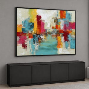 Puede incluir: Pintura de arte abstracto enmarcada en negro. La obra presenta una vibrante mezcla de colores, incluyendo turquesa, rojo, amarillo y naranja, con pinceladas que crean un efecto texturizado. La pintura está sobre un mueble negro.