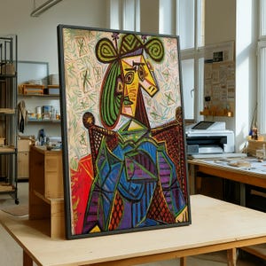 Könnte beinhalten: Gerahmtes abstraktes Gemälde im Stil von Picasso, das eine sitzende Figur mit geometrischem Gesicht und Hut zeigt. Das Kunstwerk verwendet eine lebendige Palette aus Blau, Grün, Gelb und Rot. Das Gemälde wird auf einem Holztisch ausgestellt.