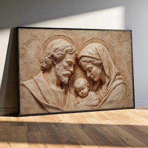 Könnte beinhalten: Gerahmte Reliefskulptur, die die Heilige Familie darstellt. Das Kunstwerk zeigt Josef, Maria und das Jesuskind, jeweils mit Heiligenschein. Das Relief ist in Beige- und Brauntönen gehalten, mit strukturierter Oberfläche und schwarzem Rahmen.