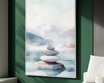 May include: A framed art print depicts a serene landscape with a stack of smooth, gray stones in the foreground, partially submerged in water. Misty mountains and a soft, cloudy sky fill the background, creating a tranquil and balanced composition. The artwork is framed in a white border.