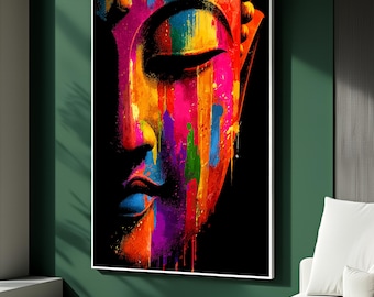 May include: A vibrant, colorful painting of a Buddha's face. The artwork features a striking blend of colors, including pink, yellow, blue, and purple, with a black background. The image is framed in white and mounted on a green wall.