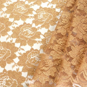 May include: Gold lace fabric with a floral pattern. The fabric is sheer and has a delicate texture.