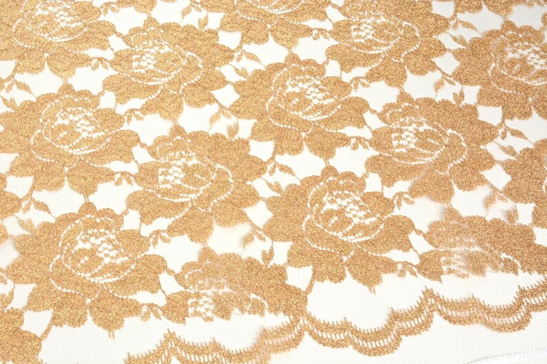 May include: Gold lace fabric with a floral pattern. The lace is delicate and intricate, with a subtle shimmer.
