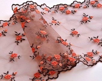 May include: Brown sheer fabric with a scalloped edge and a floral pattern in orange. The fabric is delicate and has a soft, romantic feel.
