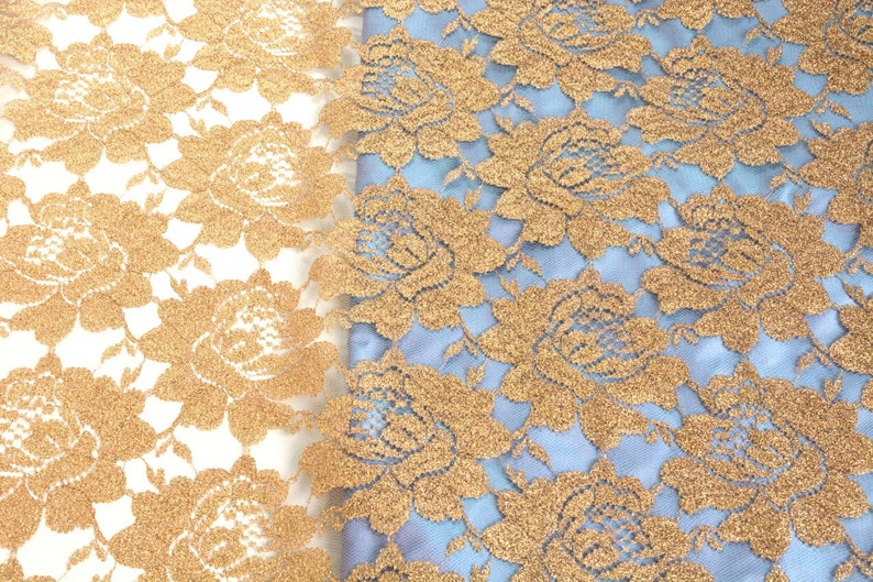 May include: Two pieces of gold lace fabric with a floral pattern. One piece is on a white background and the other is on a light blue background.