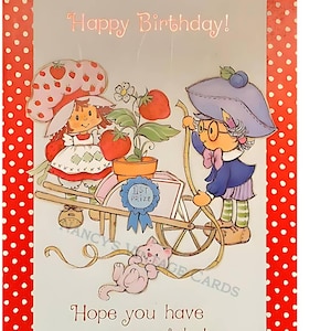 May include: A vintage birthday card with a red polka dot border. The card features cartoon characters, including a girl with a strawberry hat and another with a blueberry hat, pulling a cart of strawberries. The text reads "Happy Birthday!" and "Hope you have a special day..."