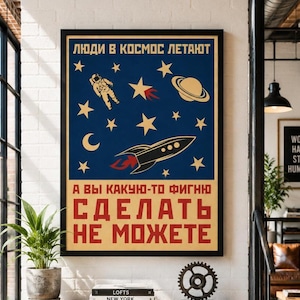 Puede incluir: Un póster enmarcado con fondo azul oscuro, un astronauta amarillo, un planeta con anillos, una luna creciente, estrellas y un cohete. El texto dice: ЛЮДИ В КОСМОС ЛЕТАЮТ A ВЫ КАКУЮ-ТО ФИГНЮ СДЕЛАТЬ НЕ МОЖЕТЕ en letras mayúsculas de color amarillo y rojo.