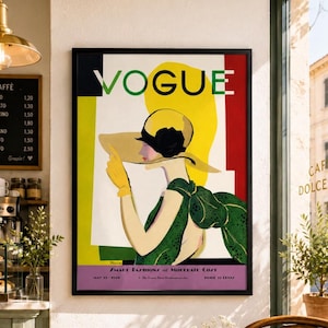 May include: Framed vintage Vogue magazine cover art. The artwork features a woman in a large hat and green dress, with the word "VOGUE" in large letters. The background includes yellow, red, and white blocks. The text "SMART FASHIONS at MOLERATE CO/T" is visible.