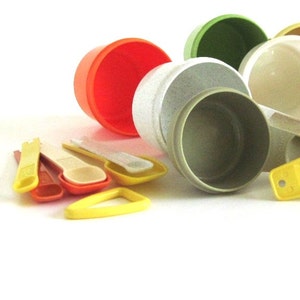 May include: A set of vintage measuring cups in various colors, including green, orange, white, and yellow. The cups are made of plastic and have a speckled finish. The set includes a variety of sizes, including 1/4 cup, 1/2 cup, 1 cup, and 2 cups.