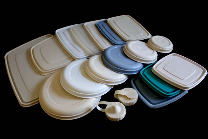 May include: A collection of various sized, round and square plastic containers with lids in beige, white, and blue.