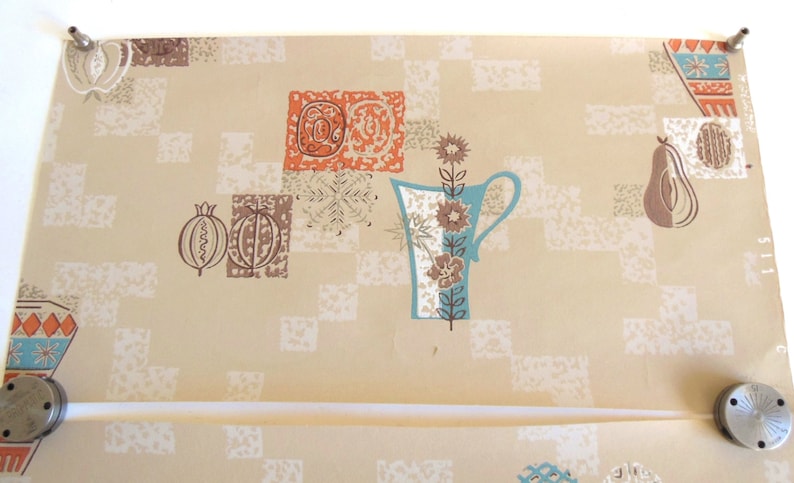 Peut inclure: Papier peint vintage avec un fond beige clair et un motif r&eacute;p&eacute;titif de formes g&eacute;om&eacute;triques bleues, brunes et orange. Le motif comprend un vase stylis&eacute; avec des fleurs, une poire et une grenade.