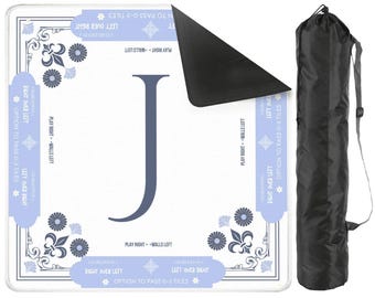 May include: A white game mat with a large blue letter "J" and floral designs, accompanied by a black carrying bag. The mat has text in blue, including "Play Right - Walls Left" and "Option to Pass 0-3 Tiles".
