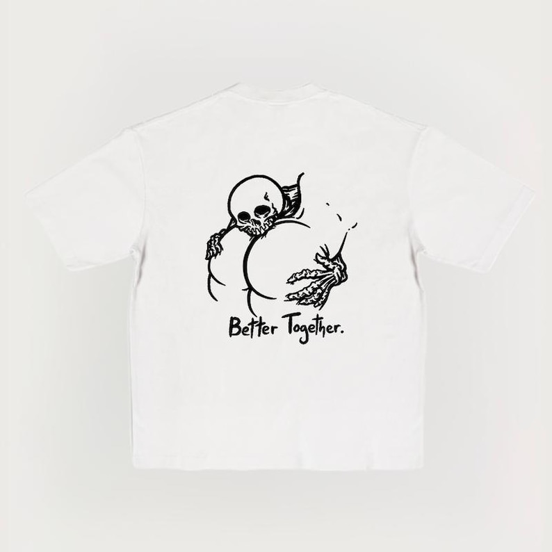Puede incluir: Camiseta blanca con un dibujo negro de un esqueleto abrazando dos c&iacute;rculos, con el texto "Better Together" debajo. El dise&ntilde;o est&aacute; impreso en la parte delantera de la camiseta.
