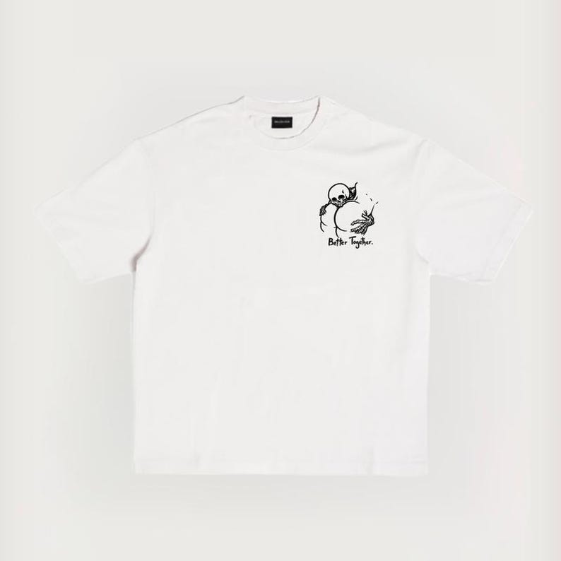 Puede incluir: Camiseta blanca con un gr&aacute;fico negro de un esqueleto abrazando una esfera, con el texto "Better Together" debajo. La camiseta tiene cuello redondo y mangas cortas. El dise&ntilde;o est&aacute; centrado en el pecho.