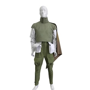 May include: A full costume displayed on a mannequin. The outfit comprises a green vest, trousers, and a cape. It also includes a white shirt, two white pouches, and a high-collared neck piece. The mannequin is set against a white backdrop.