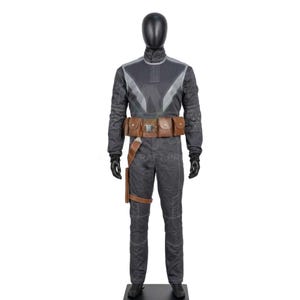 May include: A dark gray jumpsuit with a high collar, accented with lighter gray panels and stitching. The costume includes a brown leather belt with pouches and a holster. Black gloves and boots complete the outfit.