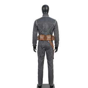 May include: A gray jumpsuit with white stitching and a brown leather belt with pouches. The costume has long sleeves and pants. The mannequin is wearing black gloves.