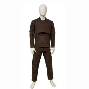 May include: A brown outfit consisting of a long-sleeved shirt, a cropped vest, and pants. The shirt has a crew neck and the pants have a straight leg. The outfit is displayed on a mannequin.