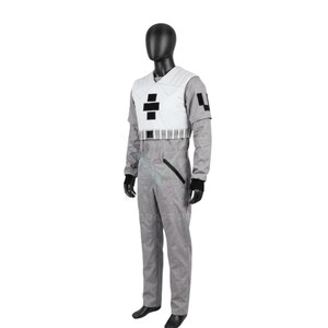 May include: A gray jumpsuit featuring a white chest vest with black rectangular accents, a V-neckline, and long sleeves. The jumpsuit includes a black diagonal pocket detail on the hip, a structured waist belt, and black wrist cuffs on a mannequin.