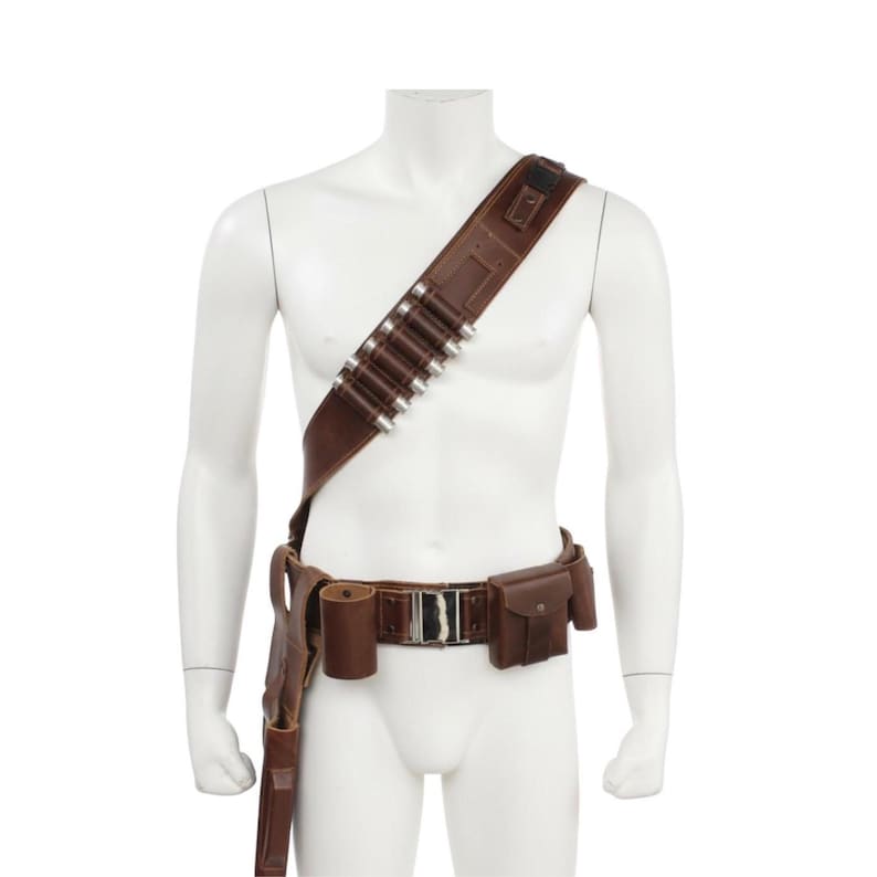 May include: Brown leather bandolier and belt set with silver bullet holders and a holster. The belt has a silver buckle and small pouches. The set is displayed on a white mannequin.