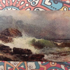 May include: Vintage postcard featuring a seascape painting. The artwork depicts a stormy ocean with crashing waves against dark, rocky cliffs. The color palette includes shades of green, brown, and gray, evoking a sense of drama and power.