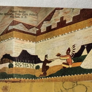Könnte beinhalten: Eine Vintage-Postkarte, die eine Szene aus dem World's Only Corn Palace in Mitchell, South Dakota, zeigt. Die Postkarte zeigt ein farbenfrohes Wandbild aus Mais, das Indianer in traditioneller Kleidung, ein Tipi und eine Landschaft mit Bergen und Maispflanzen darstellt.