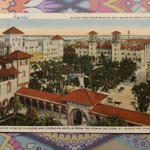 May include: Vintage postcard featuring a bird's-eye view of the Alcazar and Cordova Hotels in St. Augustine, Florida. The image showcases the Spanish and Moorish architecture of the buildings, with red-tiled roofs and ornate details. The postcard includes text at the top and bottom.