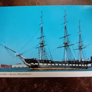 May include: A black and white sailing ship, the Old Ironsides, docked in Boston, Massachusetts. The ship has three masts and a large number of sails.