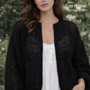 Könnte beinhalten: Ein schwarzer Cardigan mit offenem Frontdesign und lockerem Strickmuster. Der Cardigan hat lange Ärmel und einen runden Ausschnitt. Der Text "PDF PATTERN Digital Download" ist sichtbar. Der Cardigan wird über einem weißen Oberteil getragen.