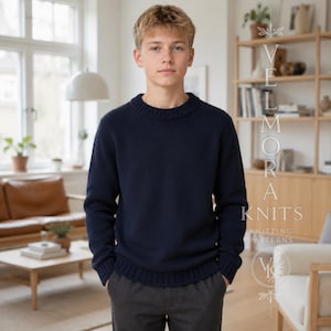 Op de afbeelding: Een donkerblauwe trui met lange mouwen, een geribbelde ronde hals en geribbelde boorden. De trui heeft een effen gebreide textuur en een rechte zoom. De tekst VELMORA KNITS KNITTING PATTERNS is zichtbaar aan de rechterkant van de afbeelding.
