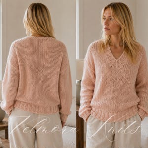 Peut inclure: Un pull à manches longues rose clair avec une texture en tricot épais, un col en V avec des détails côtelés, ainsi que des poignets et un ourlet côtelés. Le vêtement est présenté de face et de dos, montrant une coupe décontractée.
