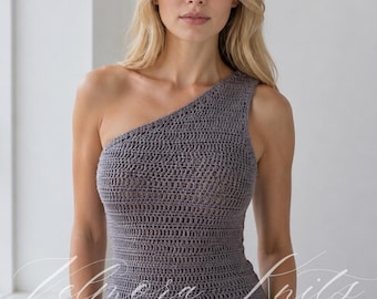 May include: A grey one-shoulder crochet top featuring a textured, hand-stitched pattern with a fitted silhouette. The garment has a single strap design and a straight hemline, with the brand name Velora Knits overlaid in white script across the front.