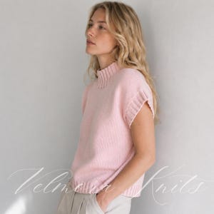 Puede incluir: Un su&eacute;ter de punto sin mangas en color rosa claro que presenta un cuello alto acanalado, aberturas para los brazos acanaladas y un dobladillo acanalado. La prenda est&aacute; confeccionada con una textura de punto suave y uniforme.