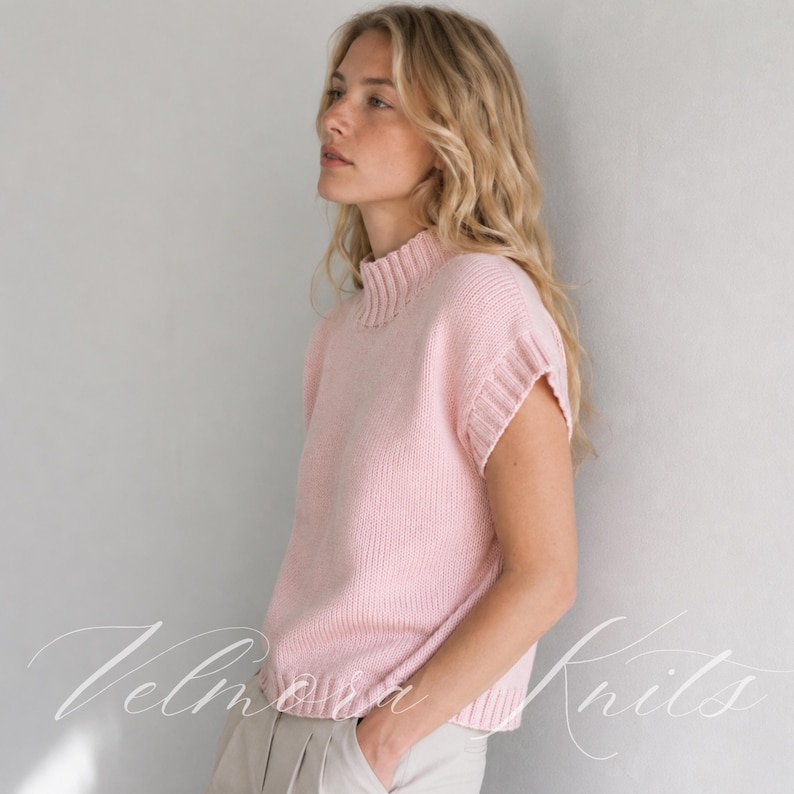 Puede incluir: Un su&eacute;ter de punto sin mangas en color rosa claro que presenta un cuello alto acanalado, aberturas para los brazos acanaladas y un dobladillo acanalado. La prenda est&aacute; confeccionada con una textura de punto suave y uniforme.