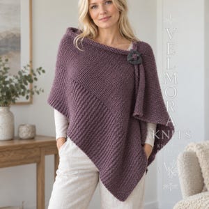 Puede incluir: Un poncho de punto malva con textura acanalada diagonal y un cierre de botón circular gris oscuro en el hombro. El texto VELMORA KNITS KNITTING PATTERN es visible en el lado derecho de la imagen en una orientación vertical.