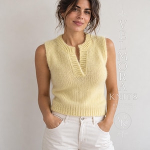 May include: A pale yellow sleeveless knit sweater vest featuring a ribbed crew neckline with a vertical slit opening. The garment has a textured, fuzzy knit construction and a ribbed hem. The text VELMORA KNITS is visible on the right side.