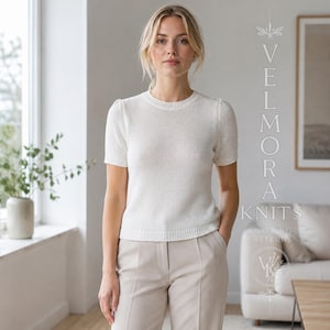 May include: A short-sleeved, off-white knit jumper with a crew neckline and ribbed trim at the collar, cuffs, and hem. The text VELMORA KNITS KNITTING PATTERNS is visible on the right side of the image, along with a circular logo graphic.