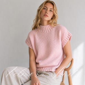 Puede incluir: Un su&eacute;ter de punto sin mangas en color rosa claro que presenta un cuello alto acanalado y ribetes acanalados a juego en las sisas y el dobladillo. La prenda est&aacute; confeccionada con un punto de jersey est&aacute;ndar, ofreciendo una textura lisa.
