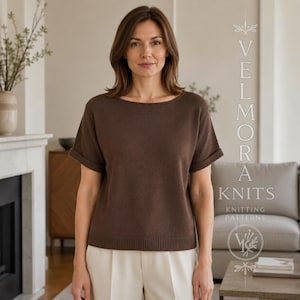 Puede incluir: Una prenda de punto marrón de manga corta con cuello ancho y mangas con dobladillo. La prenda presenta un dobladillo acanalado y una textura lisa de color sólido. El texto VELMORA KNITS KNITTING PATTERNS es visible a la derecha de la imagen.