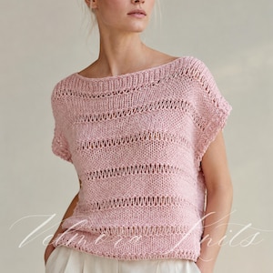 May include: A light pink knit top featuring a wide boat neckline and short sleeves. The garment is constructed with alternating horizontal bands of solid stockinette stitch and openwork eyelet rows, creating a textured, semi-sheer striped pattern.