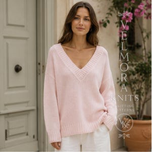 Pode incluir: Um suéter de manga comprida rosa claro com um decote em V profundo e acabamento canelado na gola, punhos e bainha. A peça de malha tem um corte relaxado e é usada com calças brancas. O texto à direita diz VELMORA KNITS KNITTING PATTERNS.