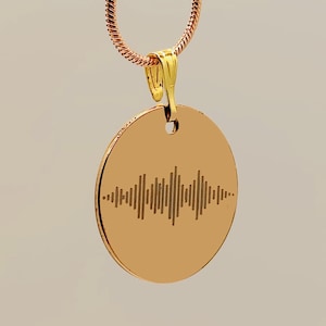 Op de afbeelding: Een roségouden ketting met een cirkelvormige hanger. De hanger heeft een gegraveerd golfpatroon. De ketting heeft een fijne ketting en een goudkleurige sluiting. De achtergrond is een neutraal beige.