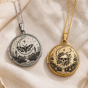 May include: Two round metal lockets on chains. The silver locket features a moth, crescent moon, and the text XVIII THE MOON. The gold locket displays a skull, floral elements, and the text XIII DEATH. Both lockets have intricate black engravings.