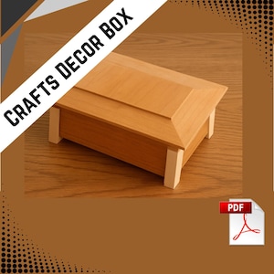 May include: A wooden craft box with a light brown finish. The box has a rectangular shape with a sloped lid and is supported by four light-colored legs. The text "CRAFTS DECOR BOX" is displayed diagonally across the top.