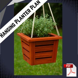 May include: A hanging wooden planter box filled with green plants. The planter is stained a reddish-brown color and has horizontal slats on the sides. The text "HANGING PLANTER PLAN" is displayed diagonally across the top left. The planter is suspended by white cords.