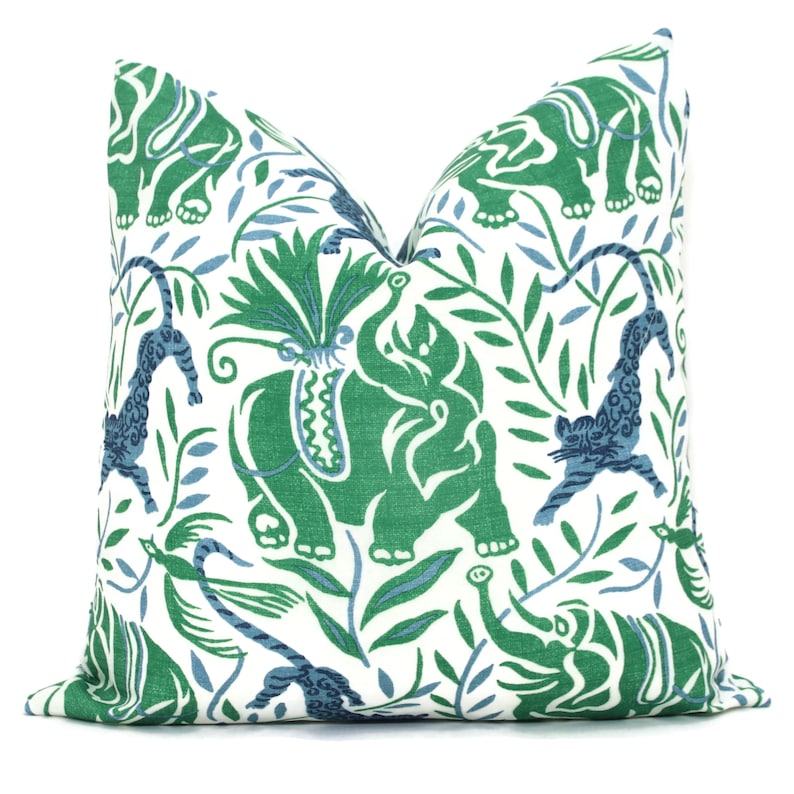 May include: A white pillow cover with a green and blue pattern of elephants, tigers, and leafy vines.