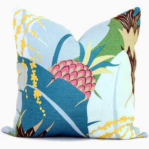 May include: A blue and white throw pillow with a tropical print featuring a large pink pineapple, green leaves, and yellow flowers.