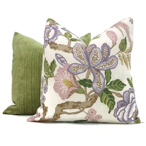 May include: Two decorative throw pillows, one with a floral pattern in shades of purple, pink, and green on a white background, and the other a solid green.