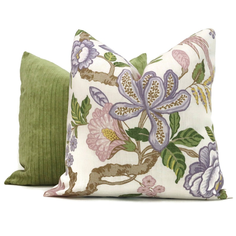 May include: Two decorative throw pillows, one with a floral pattern in shades of purple, pink, and green on a white background, and the other a solid green.