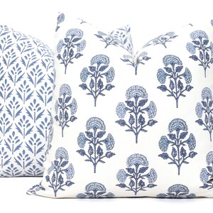 May include: Two blue and white patterned throw pillows. One pillow features a floral design, while the other has a more geometric pattern.